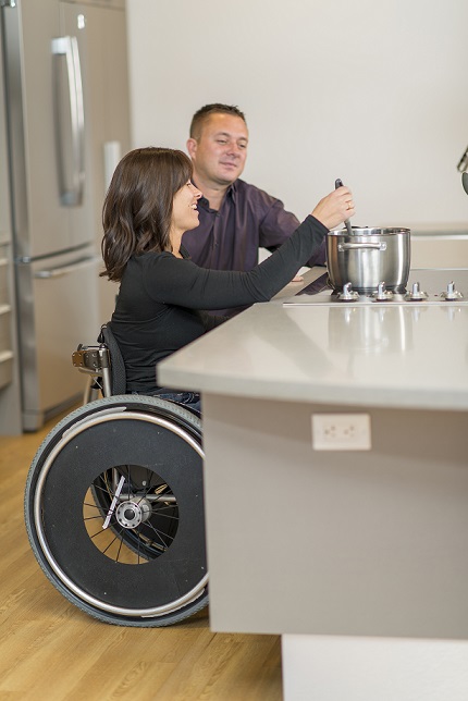 Image of a woman in a wheel chair at a stove cooking